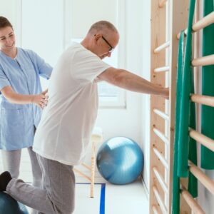 Young physiotherapist exercises in a bright medical office with his injured patient